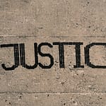 the word justice written in black ink on a concrete surface